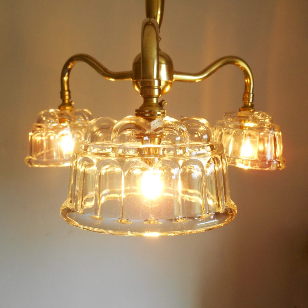 A solid brass chandelier with three glass jelly mould shades by Fiona Bradshaw Designs
