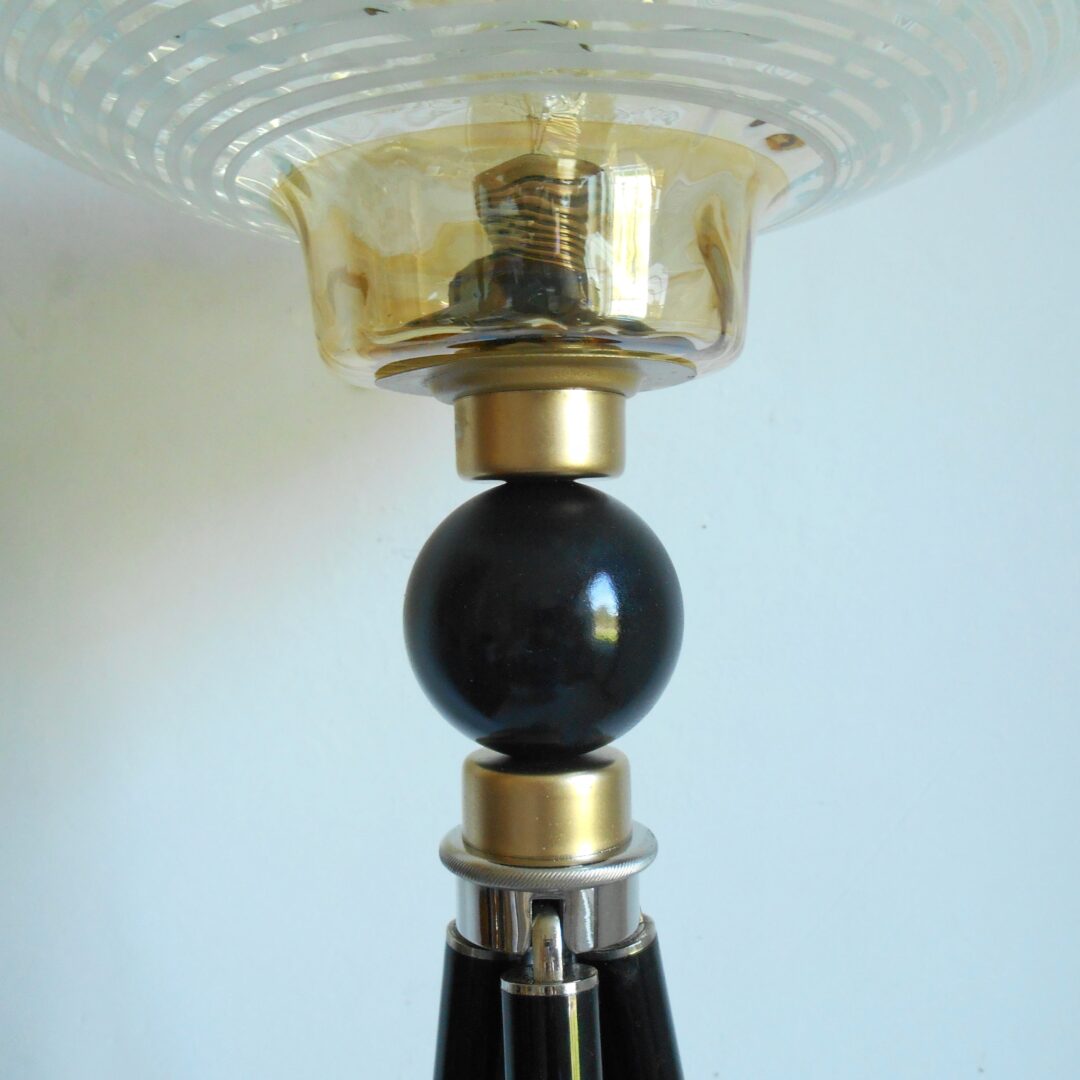 A brass tripod floor lamp with a retro glass shade by Fiona Bradshaw Designs