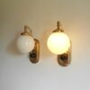 A pair of Art Deco style wall lamps with glass globe shades by Fiona Bradshaw Designs
